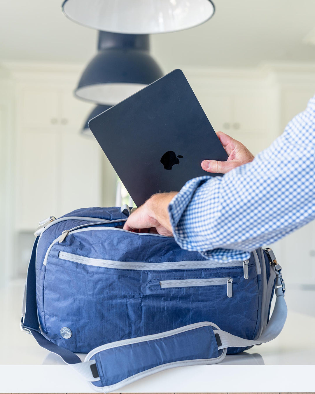 Person placing a black Apple device into offsite briefcase bag
