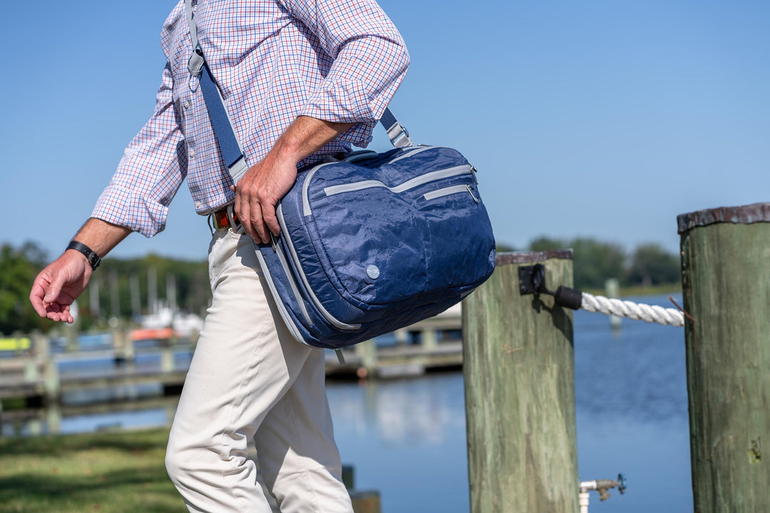 Person using Offsite messenger bag by a dock with water and sky in the background