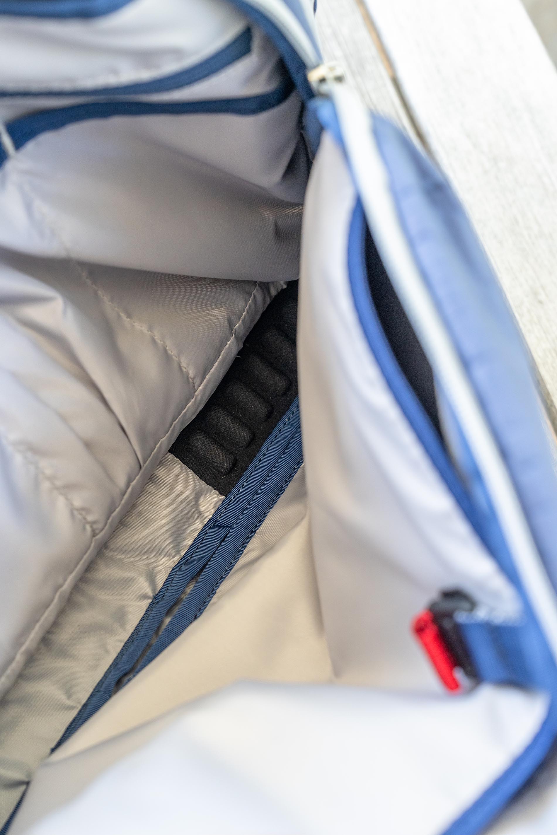 Close-up of laptop hammock on gray Offsite bag with blue zipper and red tag.