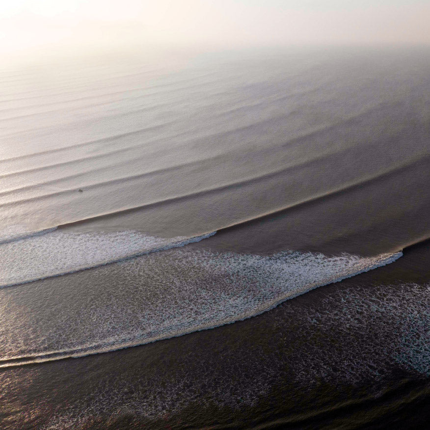 Aerial view of a hazy gray beach with waves