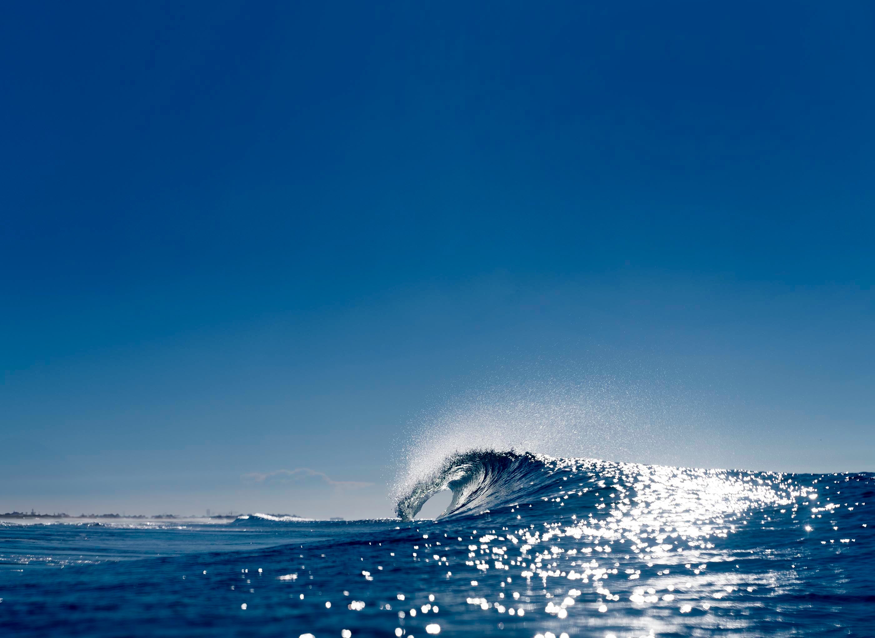 Wave crashing in the ocean with a clear blue sky