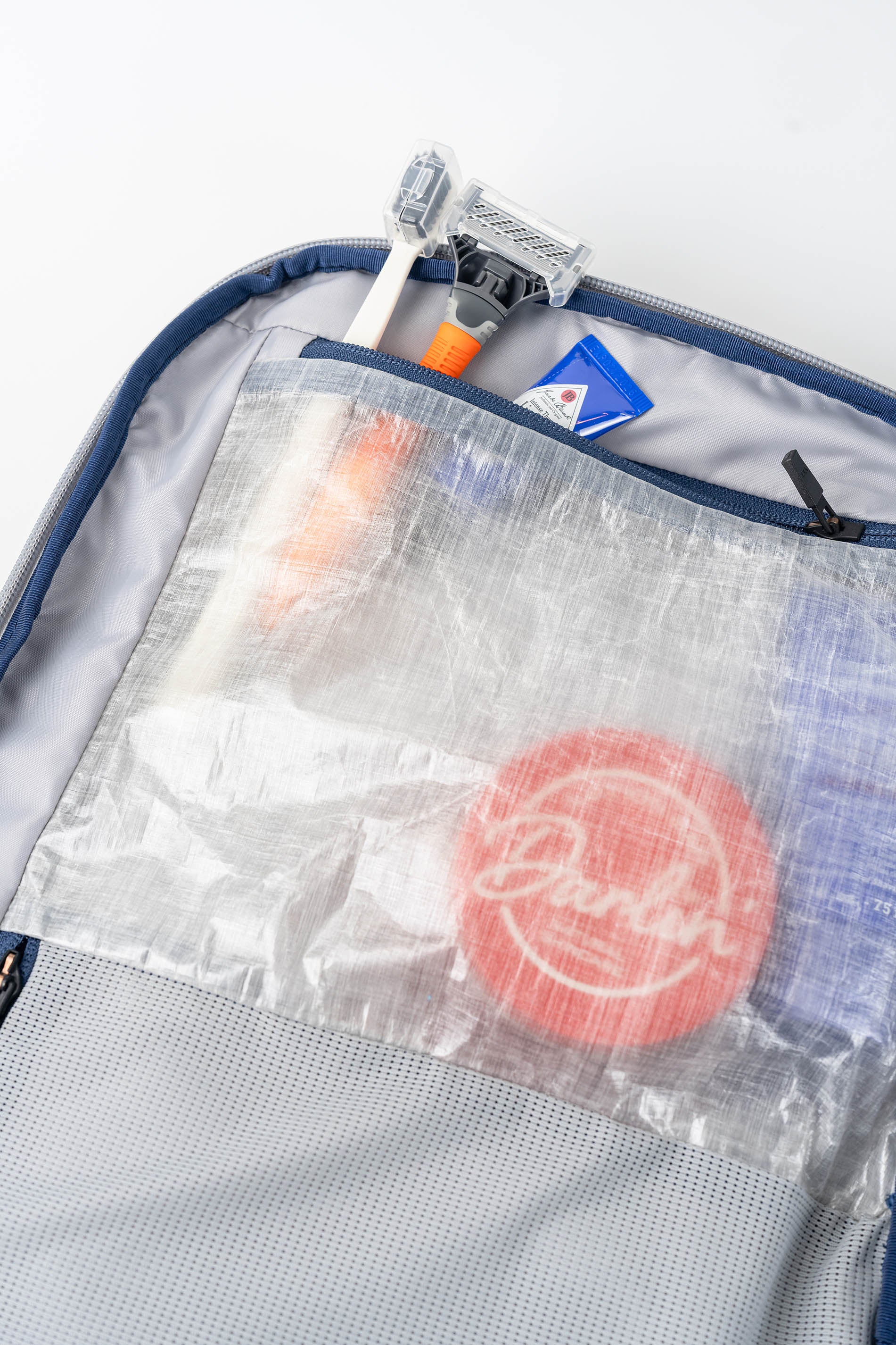 Clear waterproof dopp kit pouch with travel items including a toothbrush and toothpaste inside, on a white background.