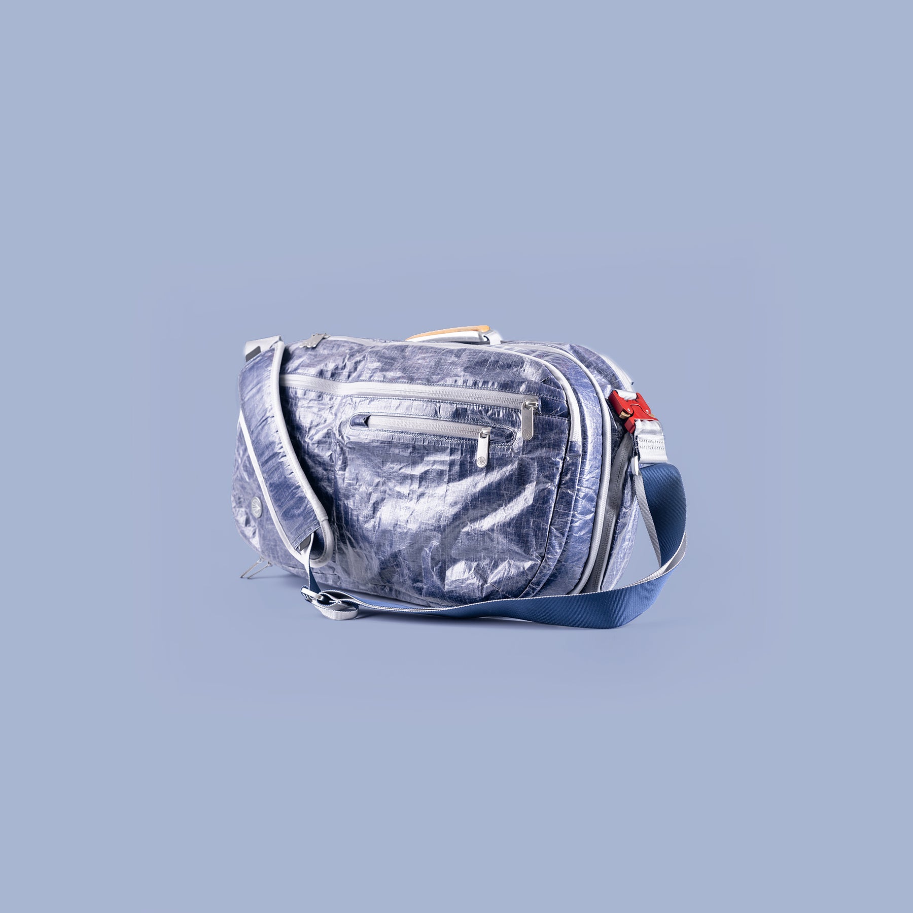 Silver metallic Offsite bag with a blue strap on a light gray background