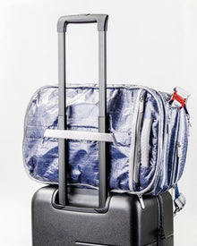 Textured Blue "White Cap" Work to Water bag with zippers attached to a suitcase on a white background