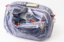 Blue "White Cap" Work to Waterbag with compartments open, revealing items like a passport and keys.
