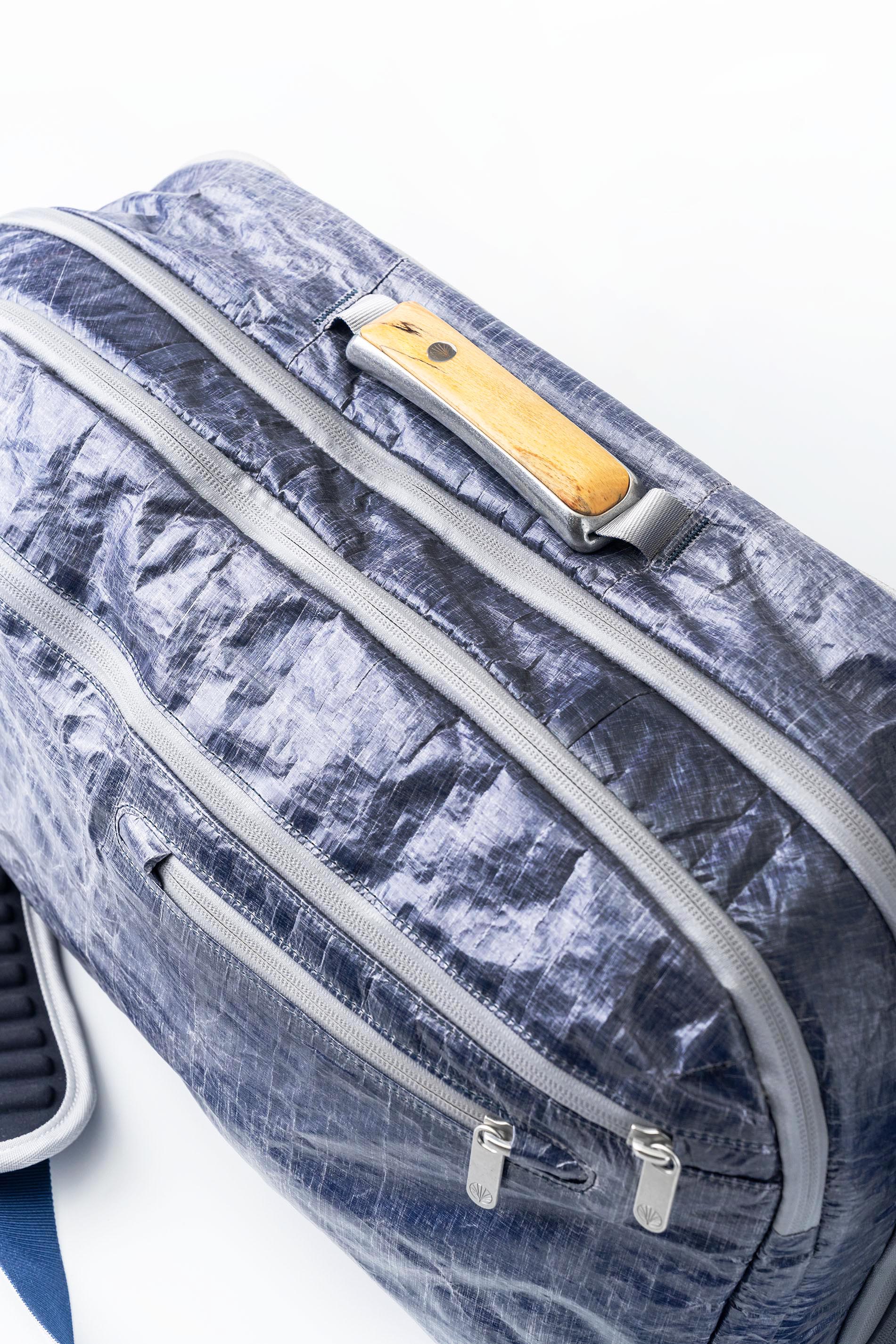 Overhead detail of Offsite Work-to-Water Bag in Whitecap colorway, showcasing Dyneema exterior and wood inlay handle integrated into contoured aluminum hardware